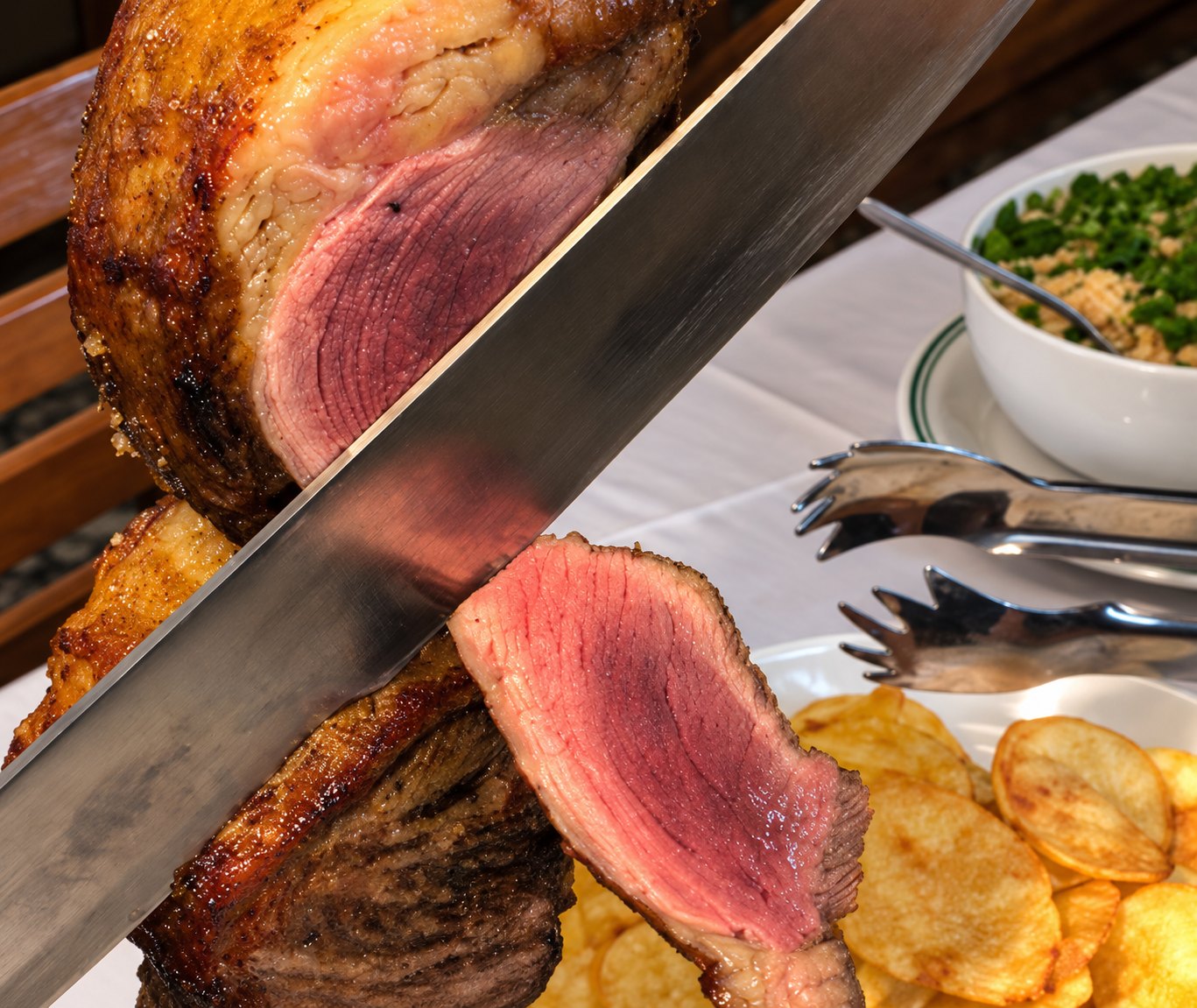 Faca fatiando a peça de carne, com o interior rosado à mostra, ao lado da farofa e das batatas